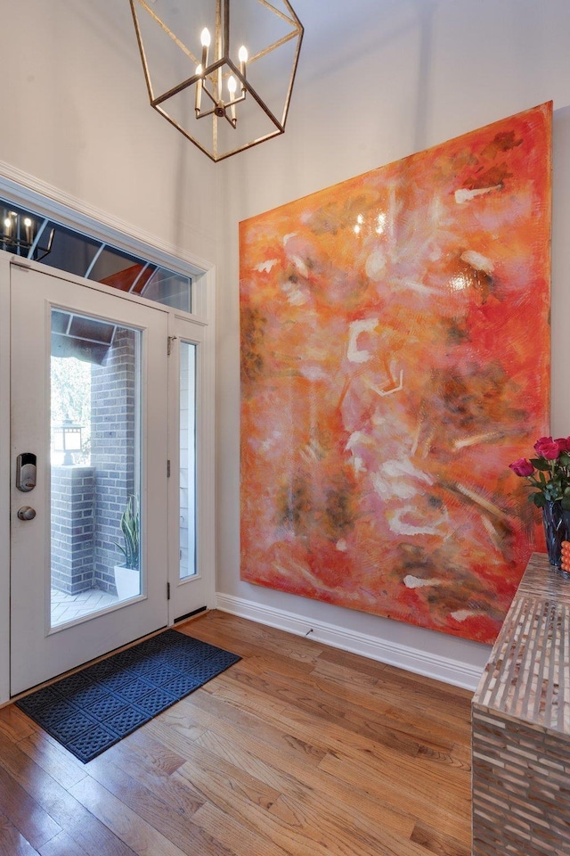 entryway with hardwood / wood-style flooring and a chandelier