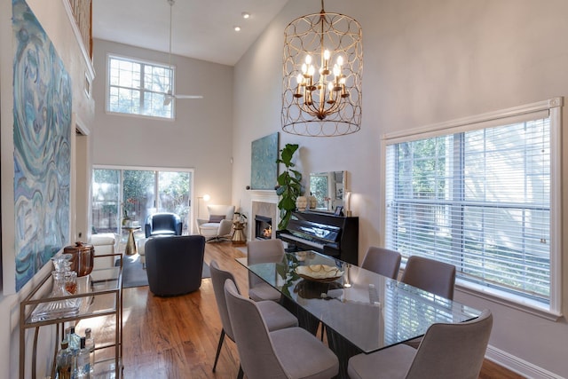 dining area with a high ceiling, a fireplace, a chandelier, and plenty of natural light