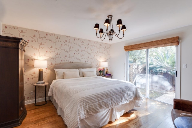 bedroom featuring access to exterior, a chandelier, and hardwood / wood-style flooring