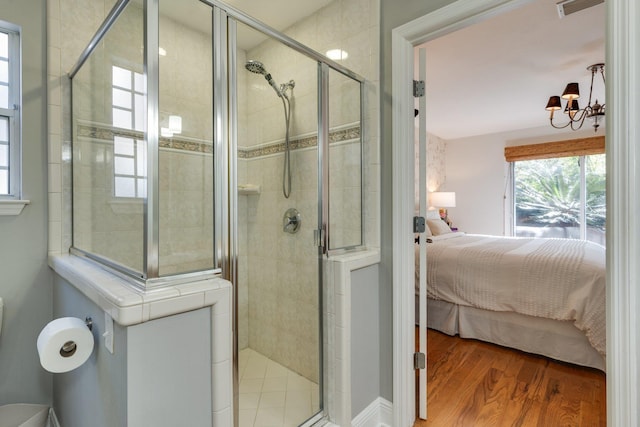 bathroom with walk in shower, an inviting chandelier, and hardwood / wood-style floors