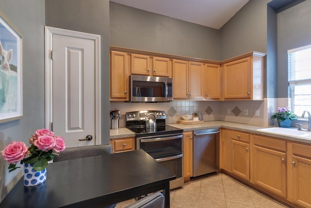 kitchen featuring stainless steel appliances, decorative backsplash, sink, and light tile patterned floors