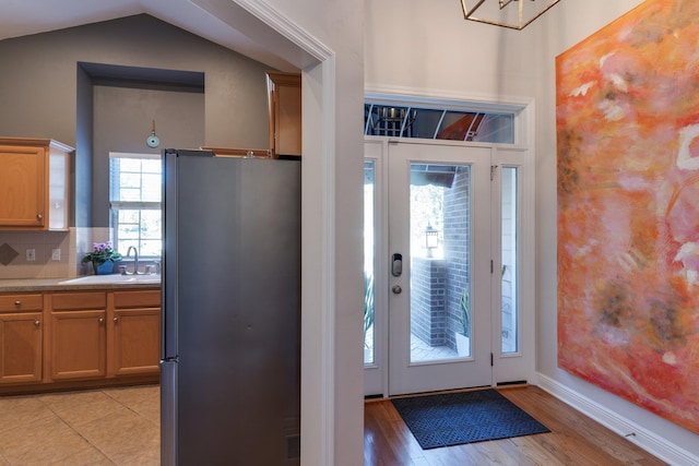 foyer with lofted ceiling, sink, and light wood-type flooring