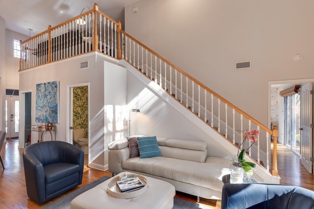 living room with hardwood / wood-style floors and a towering ceiling