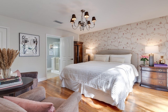 bedroom with ensuite bathroom, a notable chandelier, and light hardwood / wood-style flooring