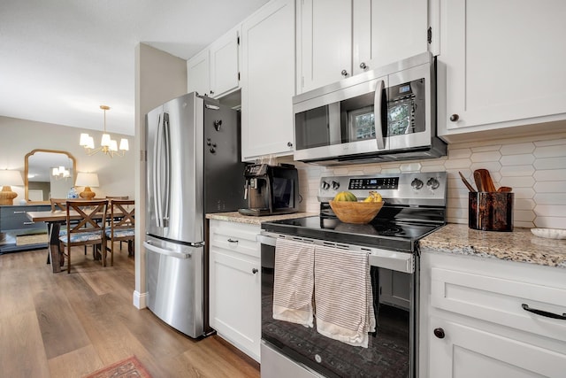 2809 Trebark Dr, Tallahassee, FL 32312 - kitchen featuring appliances with stainless steel finishes, light wood-style floors, white cabinets, tasteful backsplash, and a chandelier