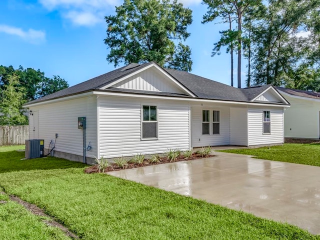 rear view of house with central AC unit, a patio, and a lawn