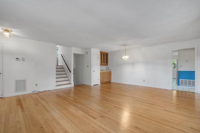2003 Chuli Nene, Tallahassee, FL 32301 - unfurnished living room featuring light wood-type flooring, stairway, and baseboards