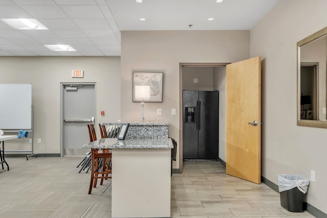 300 S Duval St Unit 612, Tallahassee, FL 32301 - kitchen with black refrigerator with ice dispenser, a kitchen bar, and light stone counters