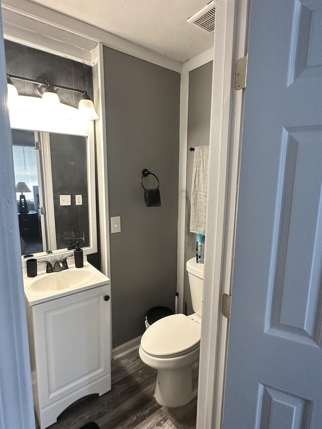 1216 Hidden Pl, Tallahassee, FL 32304 - half bathroom featuring vanity, wood finished floors, visible vents, baseboards, and toilet