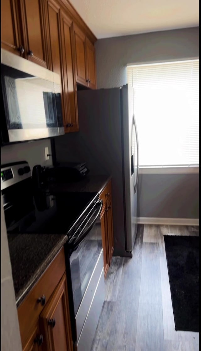 1216 Hidden Pl, Tallahassee, FL 32304 - kitchen featuring electric range, wood finished floors, built in desk, dark stone counters, and brown cabinetry