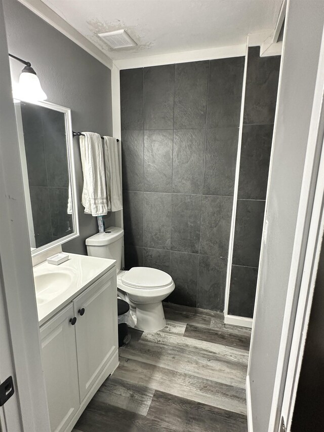 1216 Hidden Pl, Tallahassee, FL 32304 - bathroom with visible vents, toilet, wood finished floors, tile walls, and vanity