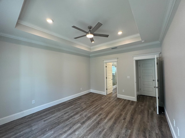 spare room featuring dark wood-type flooring, ceiling fan, a tray ceiling, and ornamental molding