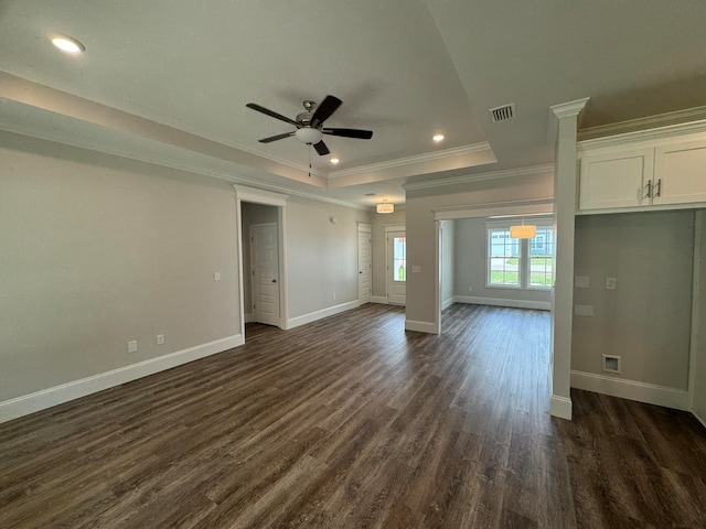 unfurnished living room featuring a raised ceiling, dark wood-type flooring, ceiling fan, and crown molding