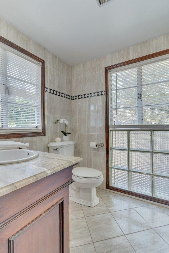 bathroom featuring vanity, plenty of natural light, tile patterned floors, and tile walls