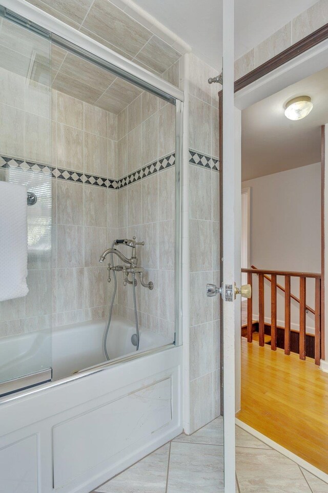 bathroom featuring wood-type flooring and shower / bath combination with glass door