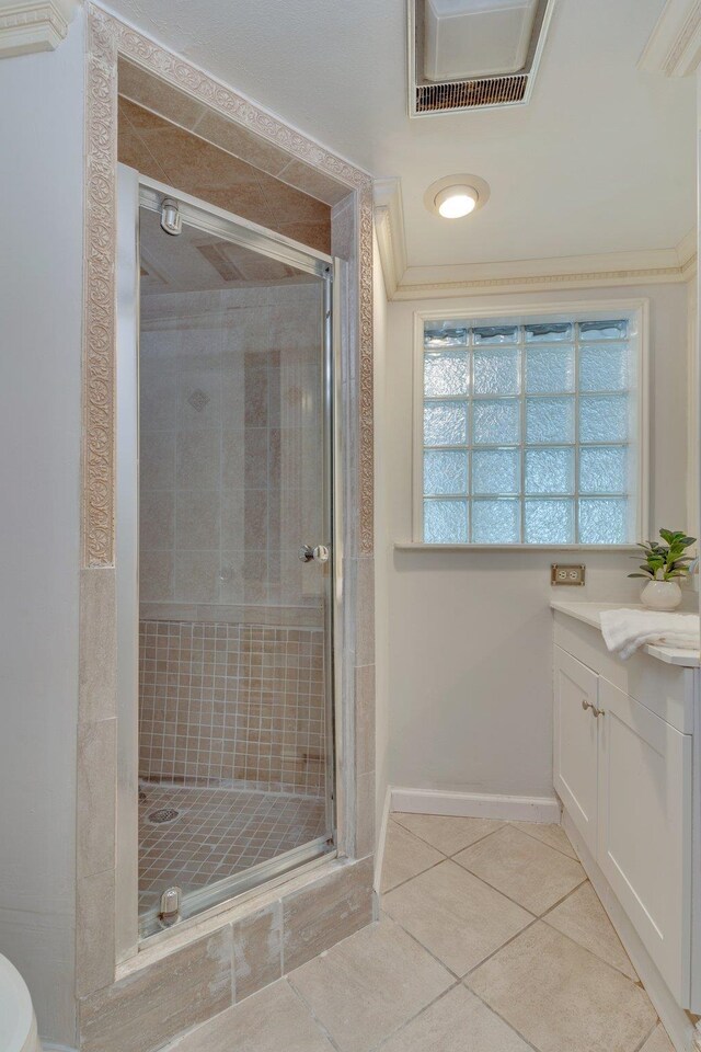 bathroom featuring vanity, an enclosed shower, tile patterned floors, and ornamental molding