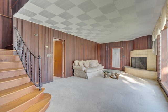 living room featuring wood walls, light colored carpet, and a fireplace