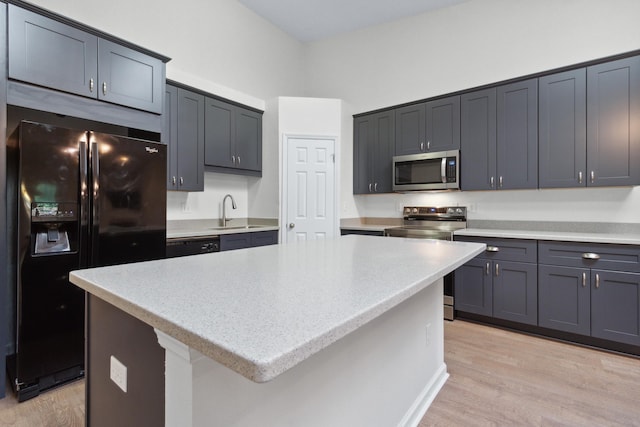 kitchen featuring sink, a center island, light stone counters, black appliances, and light hardwood / wood-style flooring