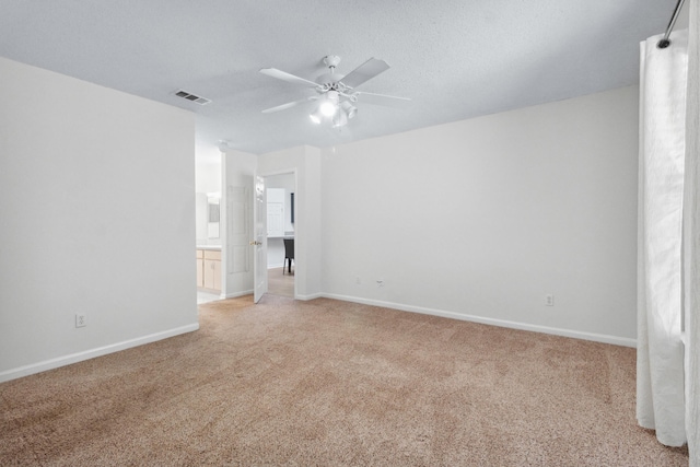 empty room featuring ceiling fan, light carpet, and a textured ceiling