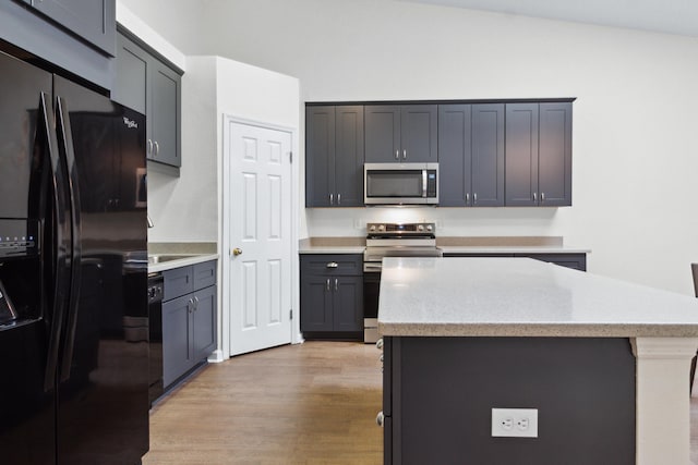 kitchen with black appliances, a center island, and light wood-type flooring