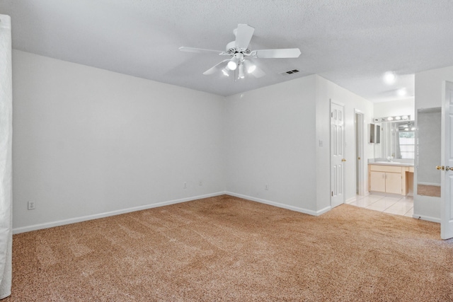 carpeted empty room with ceiling fan, sink, and a textured ceiling