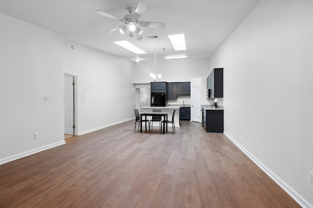 kitchen featuring ceiling fan, black fridge, dark hardwood / wood-style flooring, and a skylight