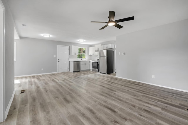 2124 Berkshire Dr, Tallahassee, FL 32304 - unfurnished living room featuring a ceiling fan, baseboards, light wood-style flooring, and a sink