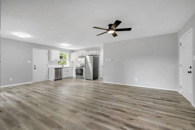 2124 Berkshire Dr, Tallahassee, FL 32304 - unfurnished living room featuring ceiling fan, light wood finished floors, baseboards, and a sink