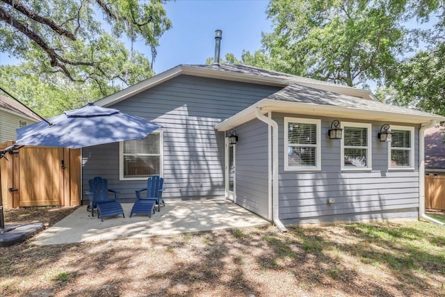 rear view of property featuring a patio, roof with shingles, and fence