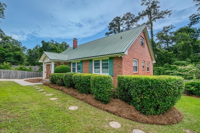 2310 Don Andres Ave, Tallahassee, FL 32304 - view of home's exterior with a chimney, brick siding, metal roof, a garage, and driveway