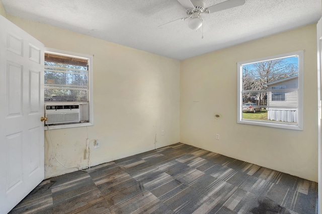 empty room featuring dark carpet, a healthy amount of sunlight, ceiling fan, and a textured ceiling