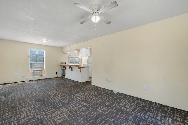 unfurnished living room featuring a textured ceiling, dark carpet, cooling unit, and ceiling fan