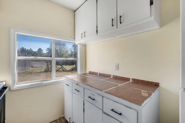 kitchen with white cabinetry and tile counters