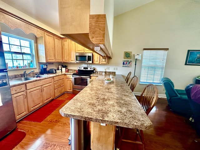 kitchen featuring light brown cabinetry, sink, a kitchen breakfast bar, kitchen peninsula, and stainless steel appliances