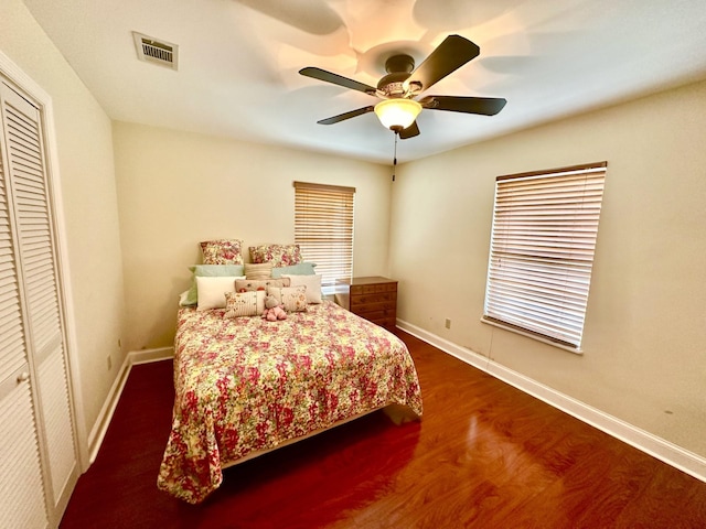 bedroom with ceiling fan, dark hardwood / wood-style flooring, and a closet