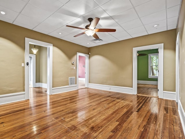 empty room featuring hardwood / wood-style flooring, a paneled ceiling, and ceiling fan