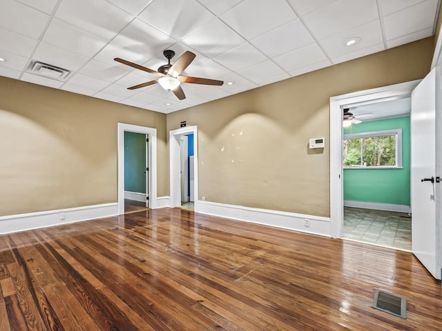 spare room with a drop ceiling, hardwood / wood-style flooring, and ceiling fan