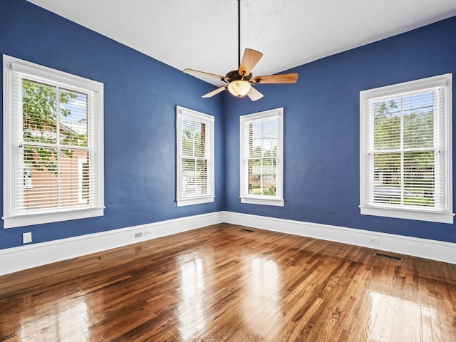 empty room featuring ceiling fan, plenty of natural light, and hardwood / wood-style floors