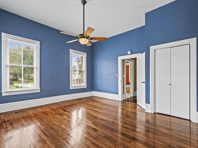 unfurnished bedroom featuring ceiling fan, dark hardwood / wood-style floors, and a closet