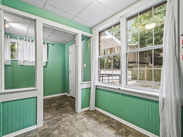 unfurnished sunroom featuring plenty of natural light and a drop ceiling