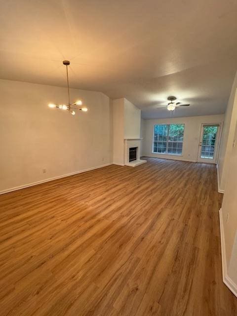 7102 Towner Trce, Tallahassee, FL 32312 - unfurnished living room featuring dark wood-type flooring, ceiling fan with notable chandelier, a brick fireplace, and vaulted ceiling