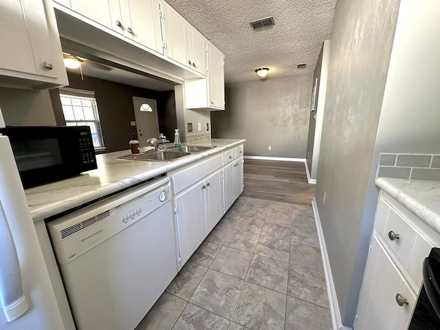 kitchen featuring white cabinetry, dishwasher, sink, and a textured ceiling