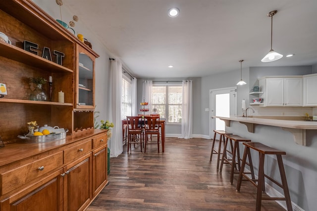 kitchen with a kitchen bar, open shelves, hanging light fixtures, and dark wood-style floors