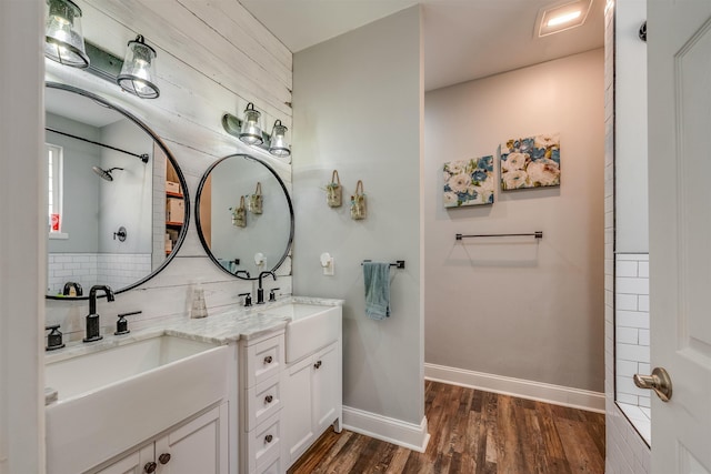 bathroom featuring double vanity, wood finished floors, baseboards, and a sink