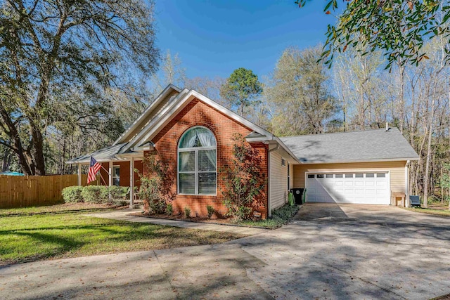 view of front facade featuring brick siding, a front lawn, fence, a garage, and driveway