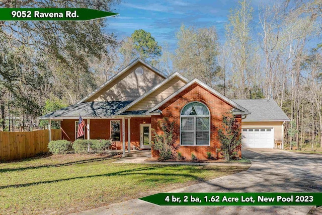 view of front of home featuring a front lawn, driveway, fence, a garage, and brick siding