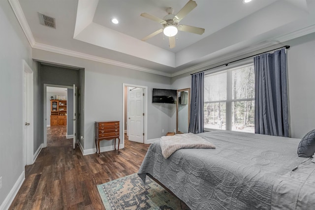 bedroom with wood finished floors, visible vents, baseboards, a tray ceiling, and ceiling fan