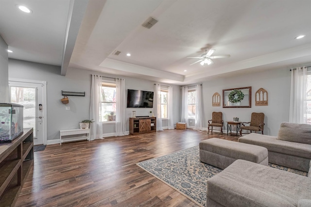 living area featuring dark wood finished floors, visible vents, a raised ceiling, and baseboards