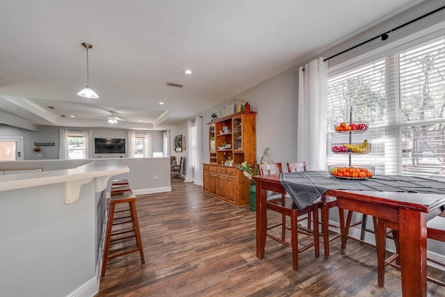 dining space featuring visible vents, baseboards, dark wood finished floors, a tray ceiling, and recessed lighting