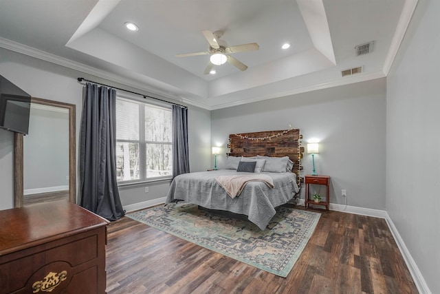 bedroom with a tray ceiling, baseboards, dark wood-type flooring, and visible vents